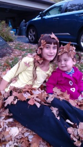 Shira and Eliana covered with leaves